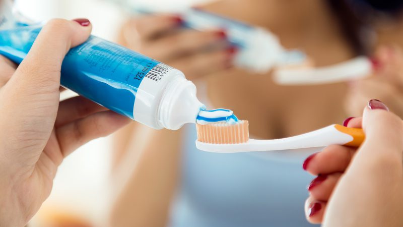 Woman squeezing toothpaste on a toothbrush
