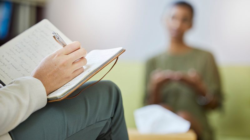 Doctor taking notes on a patient's therapy session.